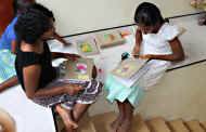 Nadisha und Sandamali im Chathura-Kinderheim verzieren die in einfaches Packpapier eingebundenen Bücher mit ausgeschnitteten Blütenmotiven.